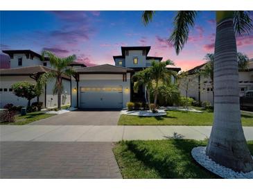 Beautiful home featuring a two-car garage and lush tropical landscaping in front at 1025 Seagrape Dr, Ruskin, FL 33570
