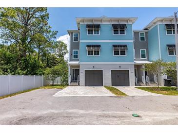 Beautiful three-story townhome with blue and gray exterior, individual garages, and well-kept surroundings at 1237 Savona Ne Dr, St Petersburg, FL 33702