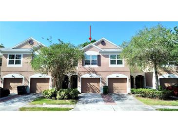 Charming townhome featuring a private garage, arched entryway, and neatly kept landscaping at 26514 Chimney Spire Ln, Wesley Chapel, FL 33544