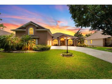 Well-maintained home featuring lush green lawn, mature trees, and a charming driveway leading to a welcoming entrance at 4022 Valrico Grove Dr, Valrico, FL 33594