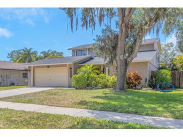 Charming home featuring a well-manicured lawn, mature trees, and a convenient two-car garage at 4915 Pennsbury Dr, Tampa, FL 33624