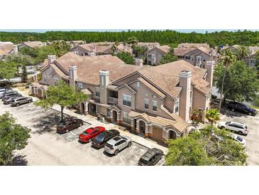 Exterior view of a condominium with multiple units and a parking lot with several cars at 18017 Villa Creek Dr # 18017, Tampa, FL 33647