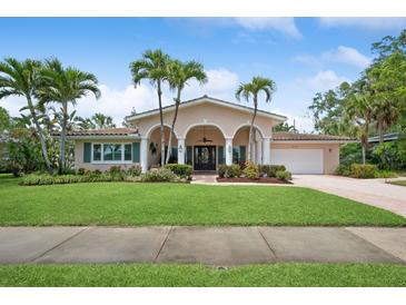 Charming home with a well-manicured lawn and palm trees, offering a welcoming curb appeal and architectural detail at 206 Corbett St, Belleair, FL 33756