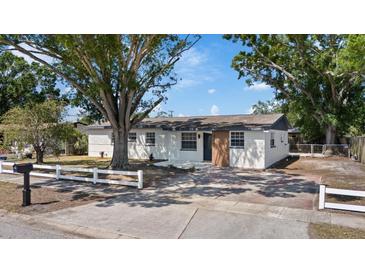 Charming single-story home with a white picket fence and mature trees in a sunny outdoor setting at 324 Country Club Dr, Oldsmar, FL 34677