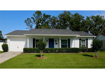Charming single-story home with a manicured lawn, vibrant blue front door, and attached garage, offers classic curb appeal at 7229 Northbridge Blvd, Tampa, FL 33615