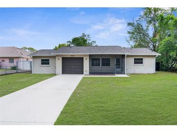Charming single-story home featuring a well-manicured lawn and a screened-in front porch at 2444 Magellan Ave, Spring Hill, FL 34608