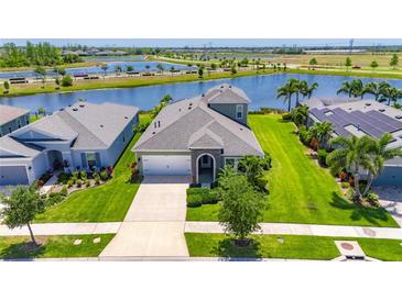 Beautiful home with well-manicured lawn and landscaping next to a scenic lake and lush greenery at 5814 Silver Sun Dr, Apollo Beach, FL 33572