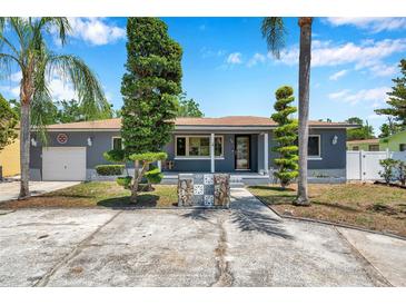 Charming single-story home featuring an inviting front porch, well-manicured lawn, and decorative landscaping at 936 Alcazar Way S, St Petersburg, FL 33705