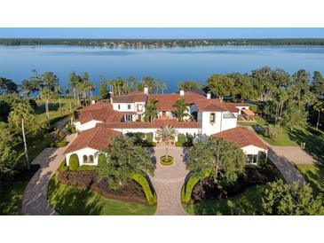 Stunning lakefront estate boasts lush landscaping, red tile roof, and circular driveway at 11865 Fort King Hwy, Thonotosassa, FL 33592