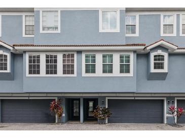Charming exterior of a blue townhome with gray garage doors and a well-maintained brick driveway at 3111 W De Leon St # 8, Tampa, FL 33609
