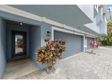 View of the unit's garage and front door, with new landscaping and brick paved driveway at 3111 W De Leon St # 8, Tampa, FL 33609