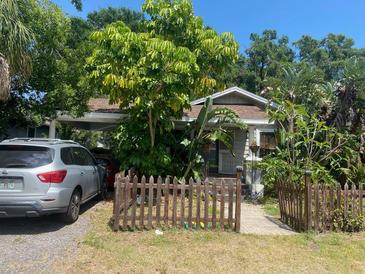 Charming single-story home featuring a wooden fence, lush landscaping, and a convenient carport at 4303 N 10Th St, Tampa, FL 33603