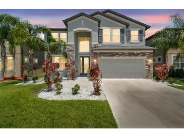 Two-story home with a two-car garage, stone accents and vibrant landscaping at 11416 Alachua Creek Ln, Riverview, FL 33579