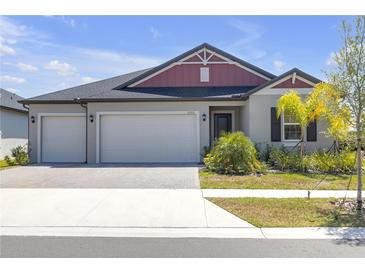 Charming single-Gathering home with a manicured lawn, brick driveway, and a three-car garage at 12572 Bergstrom Bay Dr, Riverview, FL 33579