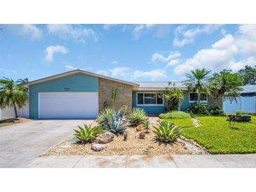 Charming single-story home with a well-manicured lawn, desert landscaping, and a two-car garage at 12965 Ridge Rd, Largo, FL 33778
