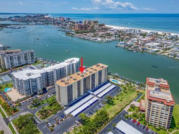 Breathtaking aerial view of waterfront condo building with boat docks, pool, and covered parking at 690 Island Way # 1011, Clearwater Beach, FL 33767