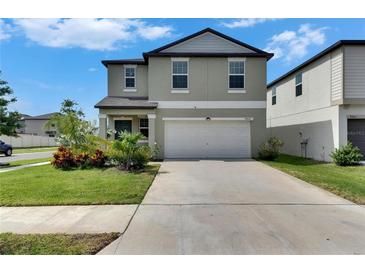 Charming two-story home with a well-manicured lawn, colorful landscaping, and a two-car garage on a sunny day at 9907 Spanish Lime Ct, Riverview, FL 33578