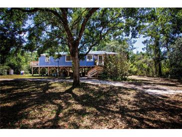 Charming stilt home featuring a quaint porch and surrounded by mature trees, offering a serene retreat at 1616 Lightfoot Rd, Wimauma, FL 33598