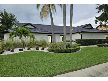 Stunning single-story home with lush green lawn, palm trees, and elegant landscaping at 7108 Pelican Island Dr, Tampa, FL 33634