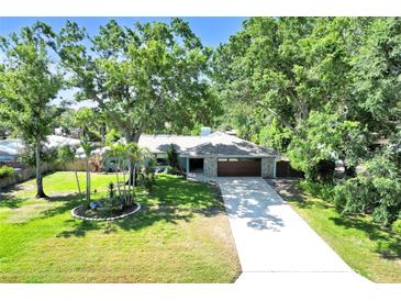 Charming home featuring a stone-accented facade, lush lawn and mature shade trees over the driveway at 1220 Pinellas Point S Dr, St Petersburg, FL 33705