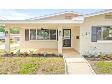 Covered front porch featuring a ceiling fan, black door, and manicured landscaping at 1323 48Th N Ave, St Petersburg, FL 33703