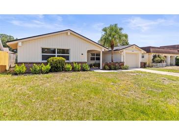 Charming single-story home featuring a palm tree, attached garage, and beautifully landscaped front yard at 3544 Edenwood Dr, Holiday, FL 34691