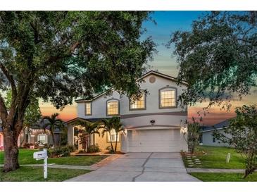 Charming two-story home with a manicured lawn, mature trees, and a well-lit driveway at 8518 Tidal Bay Ln, Tampa, FL 33635