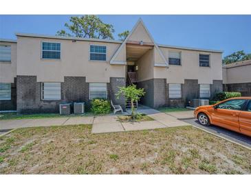 Two-story townhouse featuring a combination of beige siding and brick accents at 9031 Westchester Cir # 128, Tampa, FL 33604