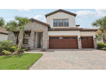 Elegant two-story home featuring a paver driveway, stone accents, and a spacious three-car garage at 21746 Amelia Rose Way, Land O Lakes, FL 34637