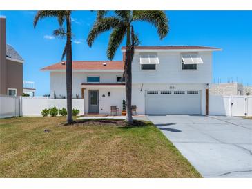 Two-story home boasts a white exterior, red roof, two-car garage, and two palm trees in the front yard at 2202 Donato Dr, Belleair Beach, FL 33786