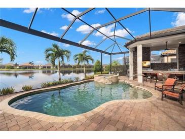 Outdoor pool with spa and covered outdoor kitchen overlooking the lake; perfect for entertaining at 13208 Malachite Dr, Bradenton, FL 34211