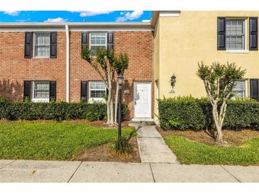 A view of the home's exterior with a brick facade, dark shutters, and small trees enhancing the front yard at 13696 Orange Sunset Dr, Tampa, FL 33618