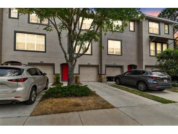 Three-story townhome showcasing a well-maintained exterior with individual garages and a vibrant red front door at 2547 Lexington Oak Dr, Brandon, FL 33511