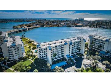 Stunning aerial view of a waterfront condo building with beautiful landscaping, a bridge, and blue water views at 7882 Sailboat Key S Blvd # 401, South Pasadena, FL 33707
