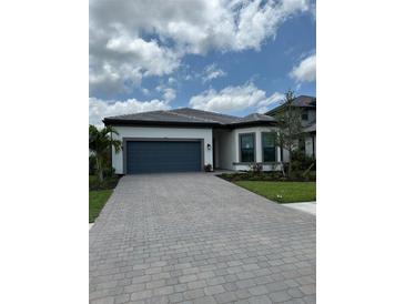 Charming single-story home with a blue garage door and paver driveway at 17116 Moonflower Dr, Venice, FL 34293