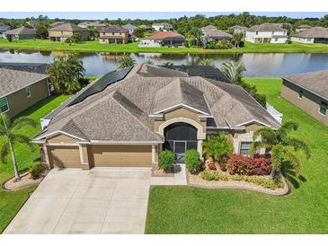 Aerial view of a beautiful house with a backyard pond and lush landscaping at 2417 Cumberland Cliff Dr, Ruskin, FL 33570