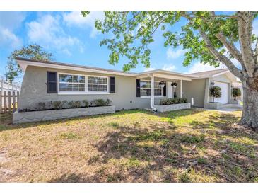 Charming single-story home featuring a well-maintained lawn and beautiful curb appeal with mature landscaping under a sunny sky at 3540 Cockatoo Dr, New Port Richey, FL 34652