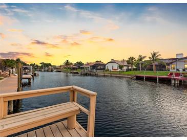 Scenic waterfront view with a wooden dock and bench, showcasing the tranquil canal and beautiful houses at 5816 Dory Way, Tampa, FL 33615