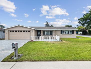 Charming single-story home featuring a well-manicured lawn, neutral paint, white picket fence, and an attached two-car garage at 5821 Thrush Dr, New Port Richey, FL 34652
