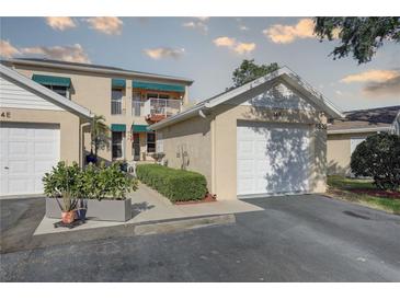 Two-story condo featuring a private balcony, vibrant green awnings, and a well-manicured, landscaped walkway at 6330 99Th N Way # 14F, St Petersburg, FL 33708