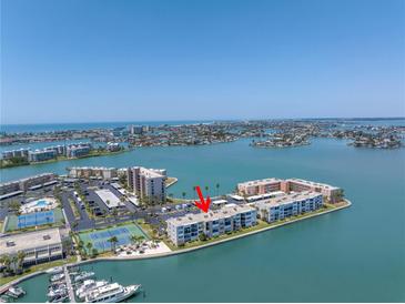 Stunning aerial view of the waterfront condo complex, featuring tennis courts and boat docks against the beautiful ocean backdrop at 7625 Sun Island S Dr # 106, South Pasadena, FL 33707