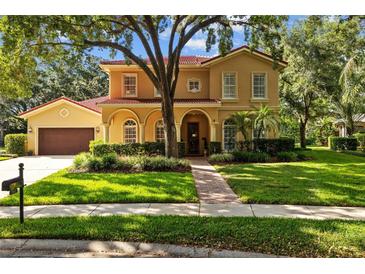 Stunning two-story home featuring a red tile roof, lush landscaping, and an inviting arched entryway at 1915 Floresta View Dr, Tampa, FL 33618