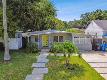 Charming single-story home features a vibrant yellow door, lush lawn, and inviting walkway at 3626 17Th N St, St Petersburg, FL 33713