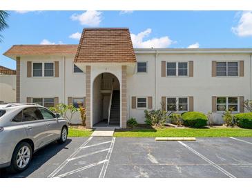 Condo building with brown roof and stairs leading to units, surrounded by landscaping at 381 S Mcmullen Booth Rd # 72, Clearwater, FL 33759