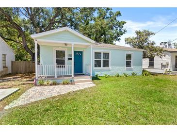 Charming light blue bungalow featuring a cozy front porch, neat landscaping, and well-maintained lawn at 3906 N Ola Ave, Tampa, FL 33603