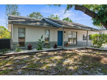 Charming single-story home featuring a blue door, inviting front entrance, and well-maintained landscaping at 7050 Jenner Ave, New Port Richey, FL 34655
