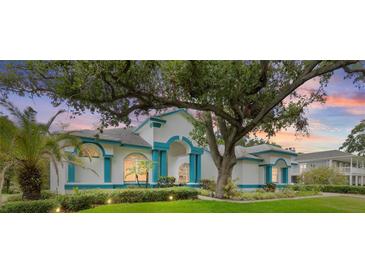Stunning exterior of a home with blue trim, lush landscaping, and mature trees providing shade and curb appeal at 7314 Hunt Club Ln, Seminole, FL 33776