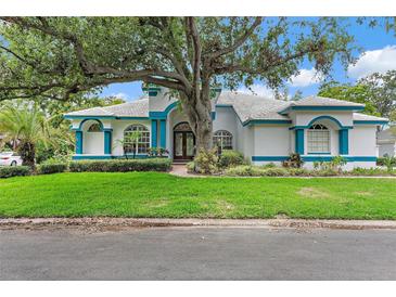 Charming home with blue trim and mature trees, showcasing its well-maintained lawn and inviting facade at 7314 Hunt Club Ln, Seminole, FL 33776