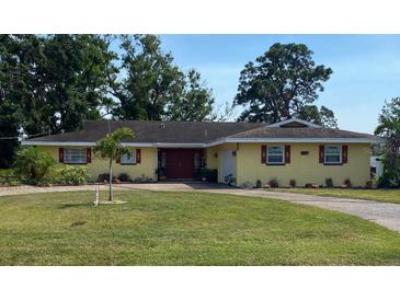 Charming single-story home featuring a well-manicured lawn and a vibrant, welcoming facade with red shutters at 836 Magellan Dr, Sarasota, FL 34243