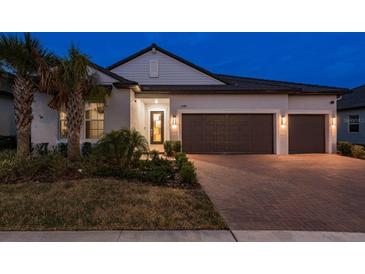 Charming single-story home with a tile roof, brick driveway, and well-manicured landscaping at twilight at 10982 Banyan Breeze Blvd, Land O Lakes, FL 34638